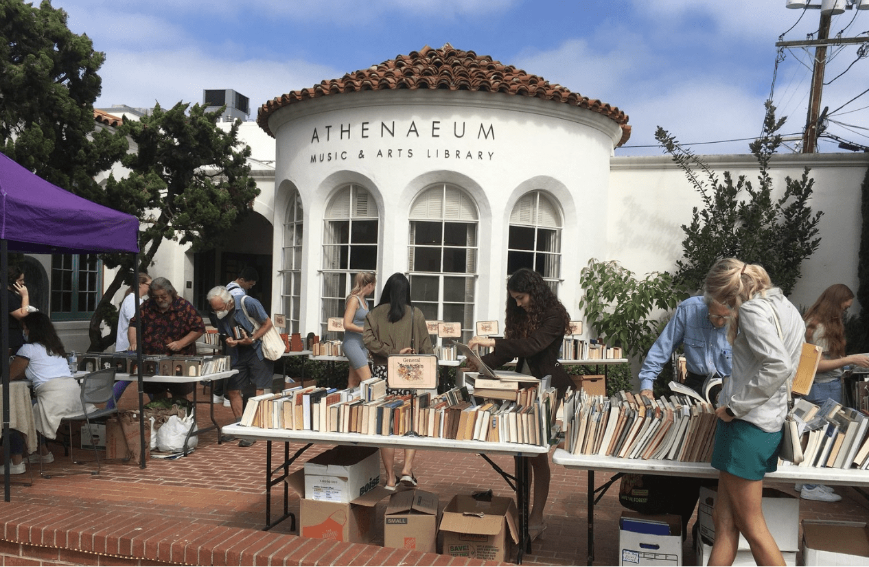 book sale outside white building with people looking through vinyl cds